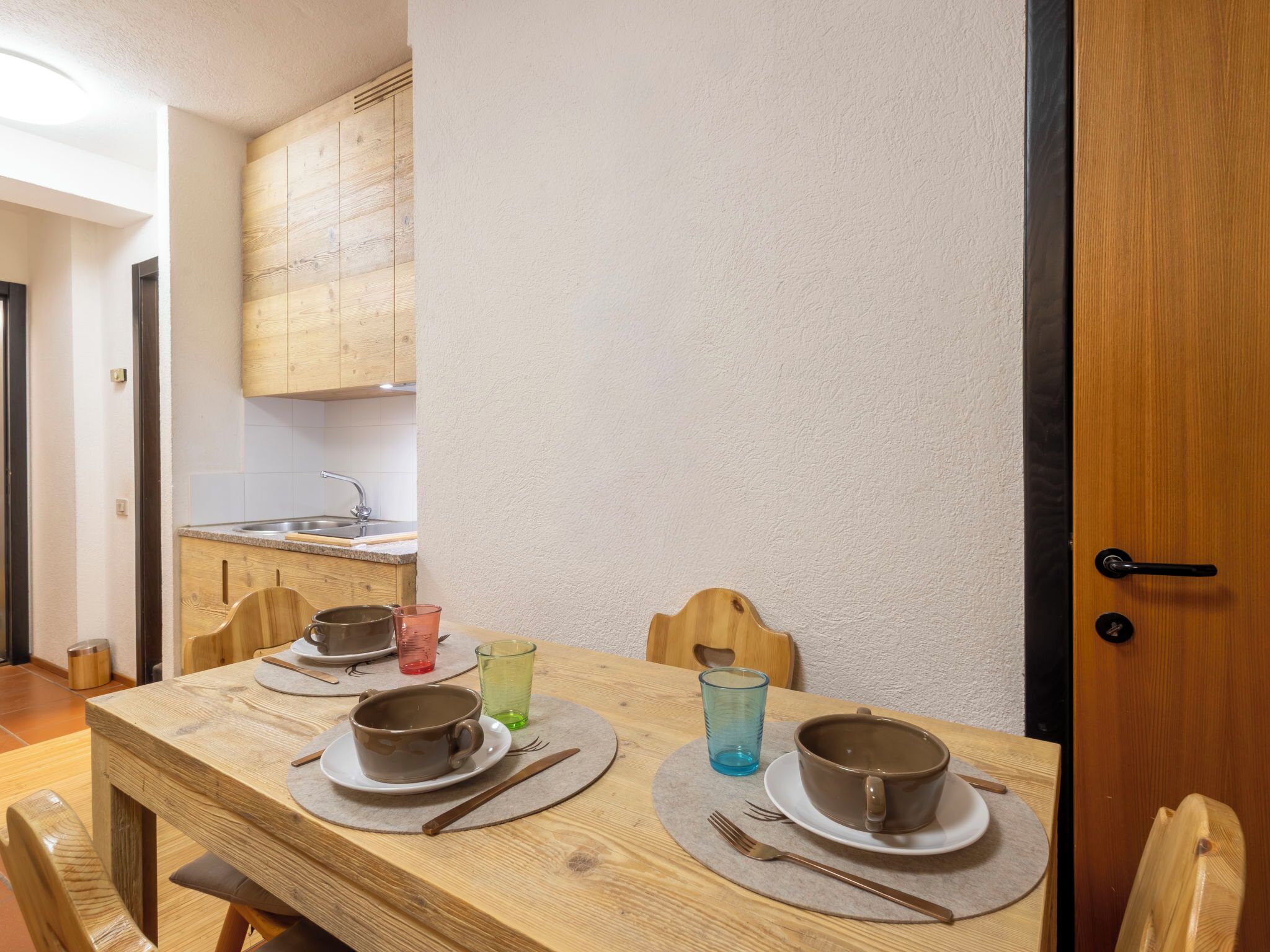 Un tavolo da pranzo in legno con piatti, posate e bicchieri.