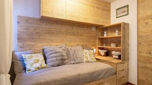 Ein gemütliches Zimmer mit einem hölzernen Kopfteil, einer Couch mit Kissen und einem Holzregal mit Dekoration.