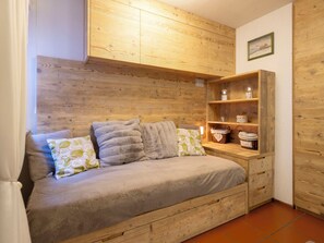 Ein gemütliches Zimmer mit einem hölzernen Kopfteil, einer Couch mit Kissen und einem Holzregal mit Dekoration.