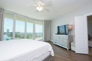 Ein Schlafzimmer mit einem großen Bett, einem Fernseher, einem Schminktisch und Blick auf die Stadt.