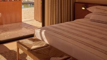 Una habitación de hotel con una cama, una lámpara colgante, vistas a una piscina y un banco de madera.