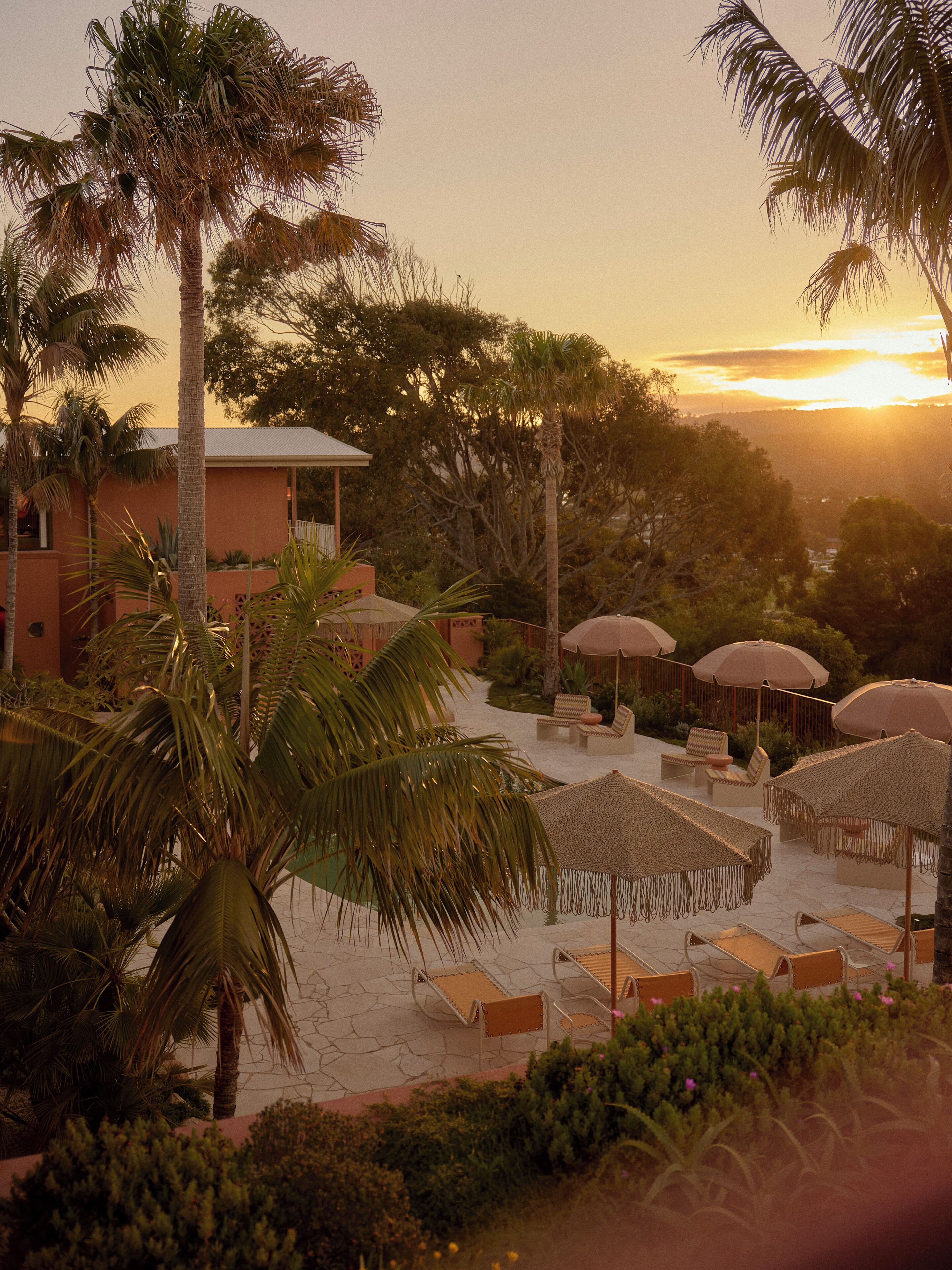 A resort with a pool area, lounge chairs, and umbrellas.