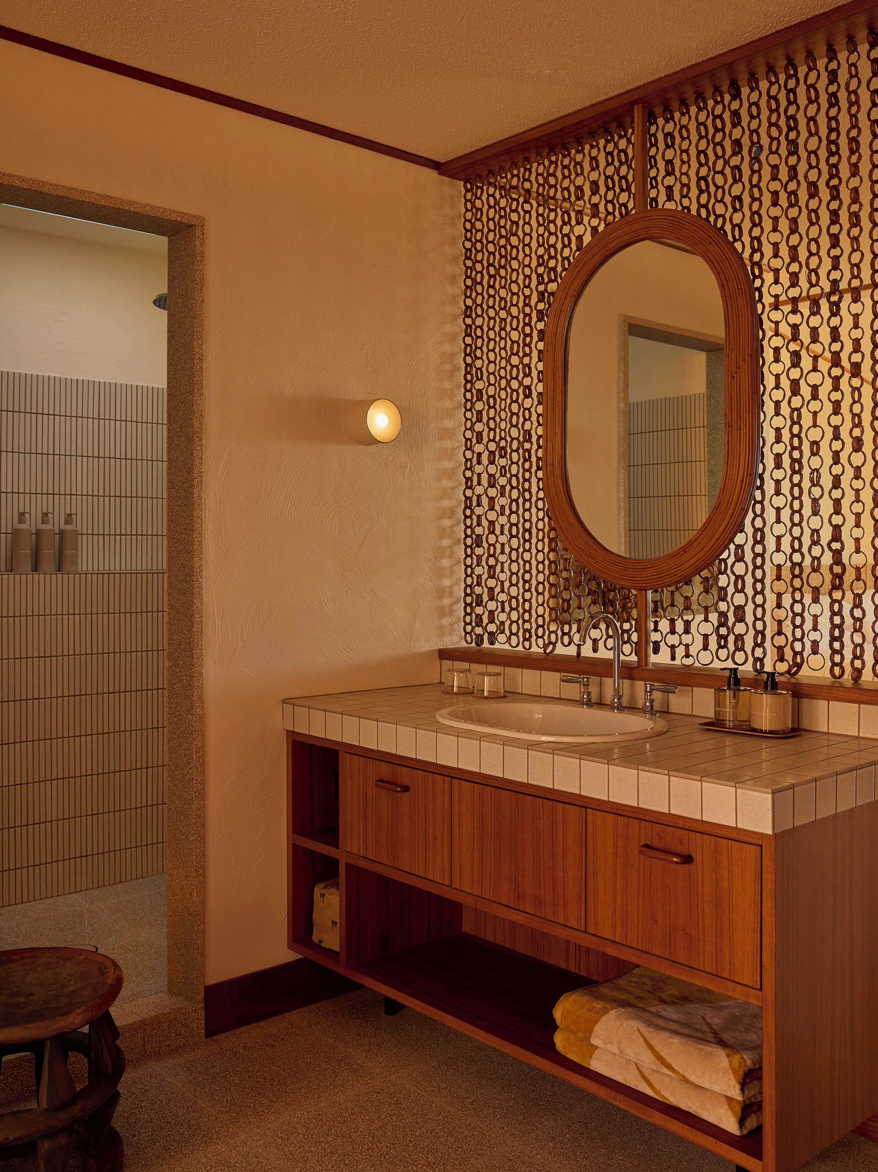 Un baño con tocador de madera, espejo redondo y pared con diseño.