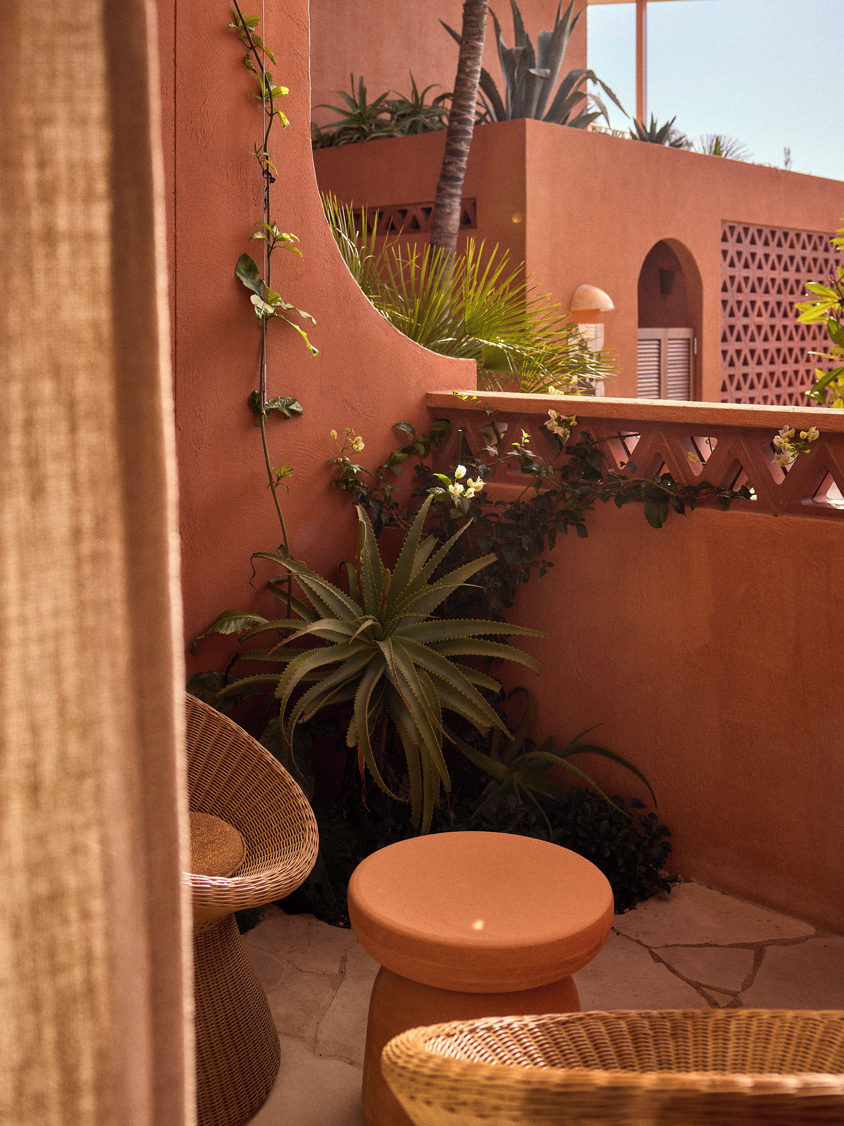 A cozy outdoor seating area with wicker furniture, a round table, and a variety of plants.