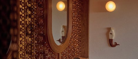 A bathroom with a wooden wall, a mirror, two sinks, and green tiled countertops.