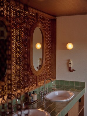 Un bagno con parete in legno, uno specchio, due lavabi e un piano di lavoro rivestito di piastrelle verdi.