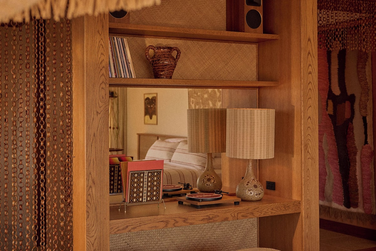 A cozy room with a wooden bookshelf, a mirror, and two ottomans.
