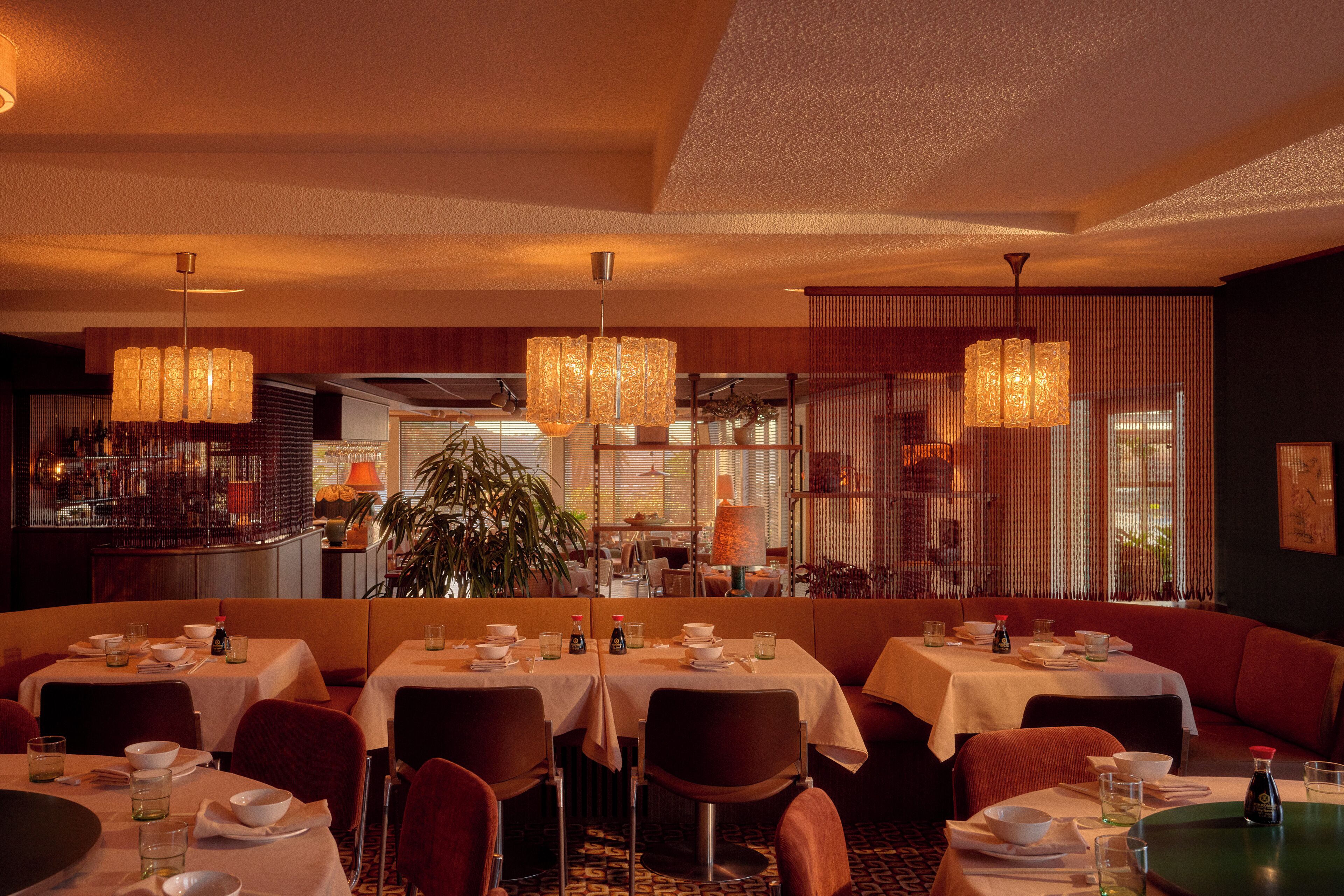 Un restaurant doté de nombreuses tables, de chaises et de luminaires suspendus.