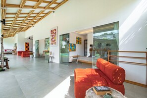 Ein großzügiger Wohnbereich im modernen Stil mit einem großen orangefarbenen Sofa, Holzboden und Kunstwerken an den Wänden.