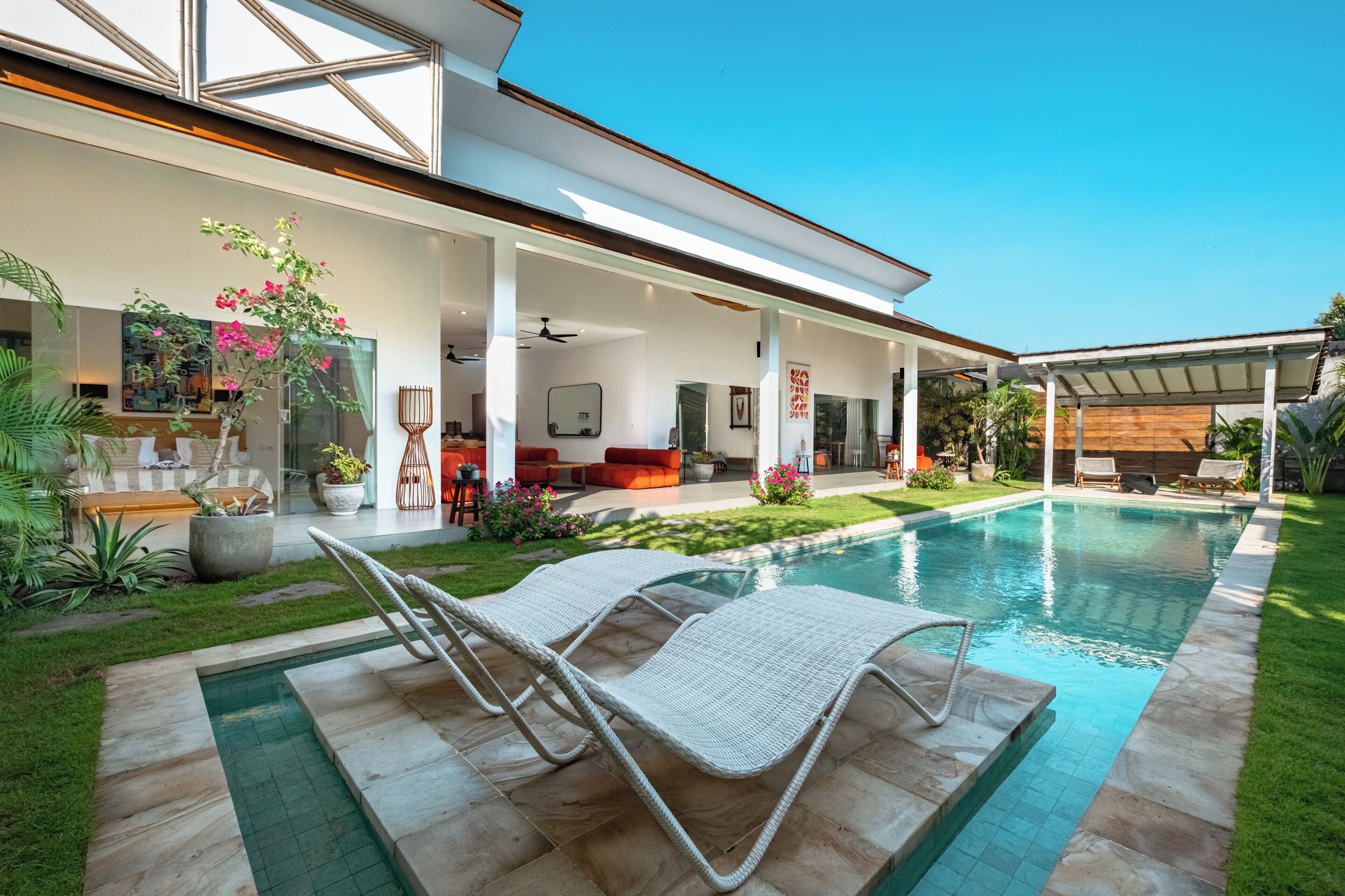 A modern house with a swimming pool, outdoor seating, and a covered patio area.