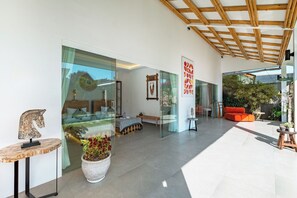 Ein modernes Interieur mit einer Glaskabine, einer Holzbalkendecke und einer Sitzecke mit einem roten Sofa.
