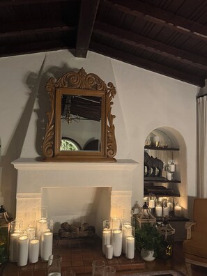 Ein Kamin mit mehreren Kerzen, ein Spiegel mit aufwendigem Rahmen und ein Regal mit Dekoration.
