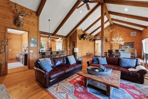 A spacious living room with leather sofas, a coffee table, and a wooden ceiling with exposed beams.