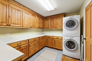 Een keuken met houten kastjes, een wasmachine en droger en een vloerkleed met patroon.