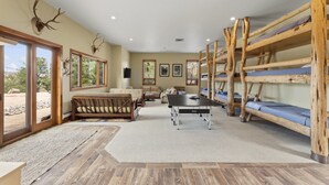 A room with bunk beds, a sofa, a table, and a large window. - Secluded Mountain Ranch Home on 217 acres | Views | Fireplace | Hot Tub | Trout Pond (Silt)