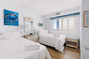 Une chambre d’hôtel avec deux lits, une fenêtre donnant sur un beau paysage, un tableau et un élément décoratif mural.