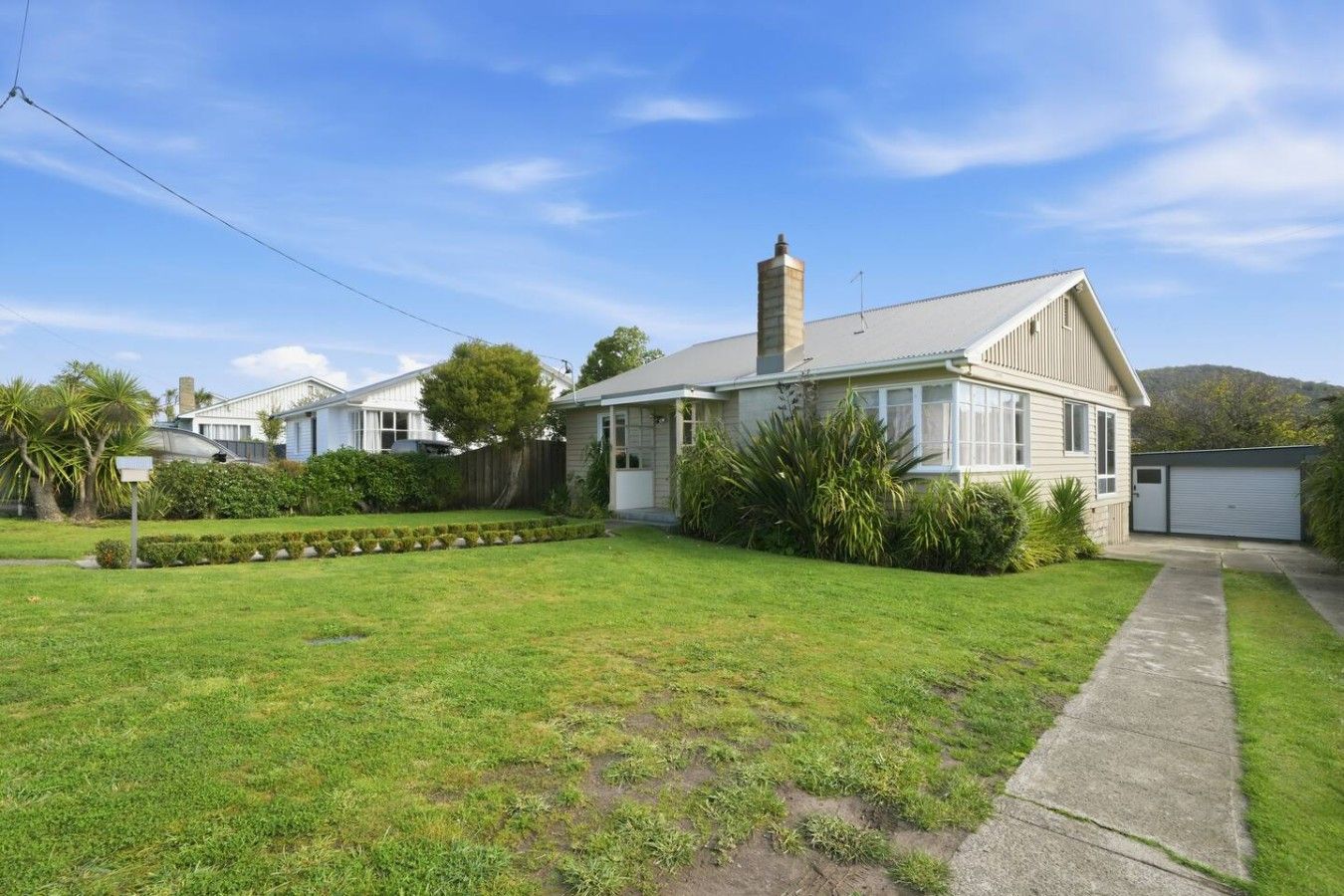 A residential property with a well-maintained lawn, a garage, and a detached house with a chimney.