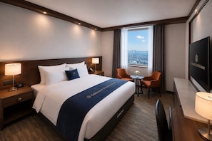A hotel room with a large bed, two bedside tables with lamps, a desk with a chair, a television, and a window with a city view. - Goldcoast hotel Incheon (Incheon)