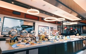 A buffet area with multiple serving stations, overhead circular lighting, and a modern interior design.