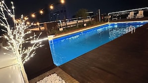 A swimming pool with a wooden deck, white pebbles, and string lights. - Goldcoast hotel Incheon (Incheon)