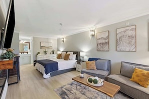 A modern hotel room with a bed, two sofas, a coffee table, and artwork on the walls.