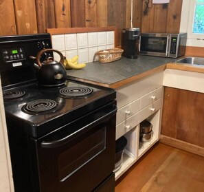 A kitchen with a black stove, microwave, and a wooden cabinet.