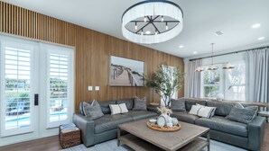 Een moderne woonkamer met een modulaire bank, een houten salontafel en een groot raam met gordijnen.
