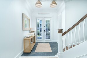 A hallway with a wooden bench, a mirror, a rug, and a staircase. - Waverly Oasis at Destin Pointe | Private Pool, Resort Amenities & Beach Access (Destin)