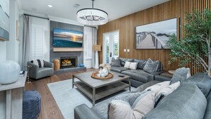 Een moderne woonkamer met een open haard, een grote flatscreen televisie en een comfortabele zithoek.