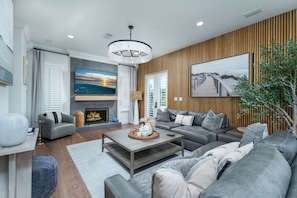 A modern living room with a fireplace, a large flat-screen TV, and a comfortable seating area. - Waverly Oasis at Destin Pointe | Private Pool, Resort Amenities & Beach Access (Destin)