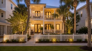 Een huis met twee verdiepingen, omringd door een witte picket fence, met een balkon en een voortuin.