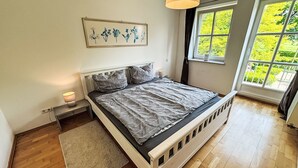 Ein Schlafzimmer mit Bett, Nachttischen, einem Fenster mit Blick auf Grünflächen und einer Hängelampe.