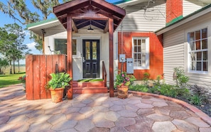 A house with a covered porch, a front door, and a brick chimney.
