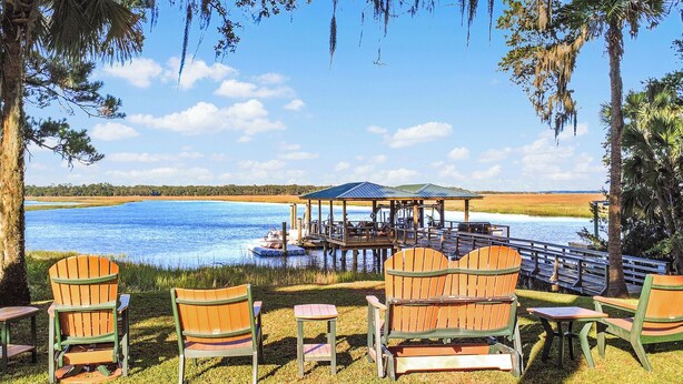 Ein Deck am See mit Stühlen und einer Laube mit Blick auf das Wasser.