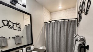 Un baño moderno con tocador, espejo, perchero, inodoro y cortina de ducha.