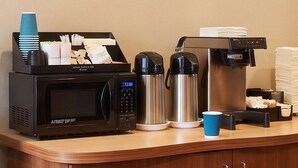 Une petite cuisine équipée d’un four à micro-ondes, d’une machine à café et d’un thermos.