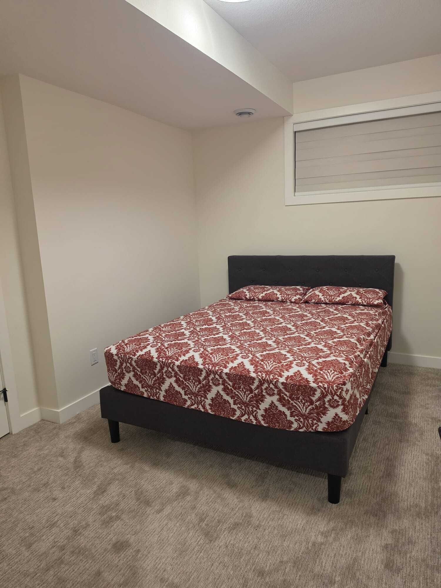 Un dormitorio con cama, luz de techo y ventana con persianas.