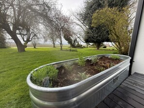 Un bac à fleurs en métal, orné de plantes, posé sur une terrasse en bois.