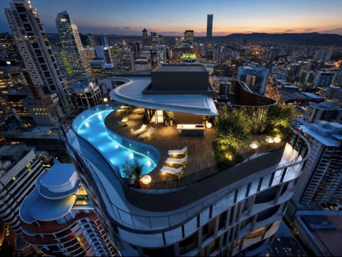 A rooftop pool with lounge chairs and a covered area, surrounded by high-rise buildings.