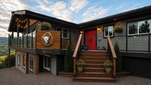 Un bâtiment moderne à deux étages, doté d’une façade en bois, d’une porte rouge et d’un balcon décoré de guirlandes lumineuses.