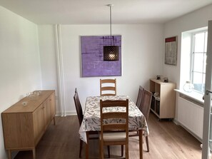 A dining area with a table set for four, a wooden cabinet, and a window with a view.