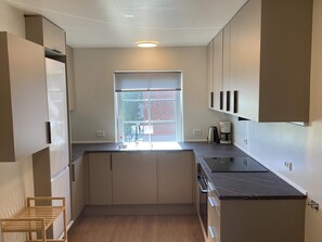 Cocina compacta con ventana, armarios empotrados, encimera y cafetera.