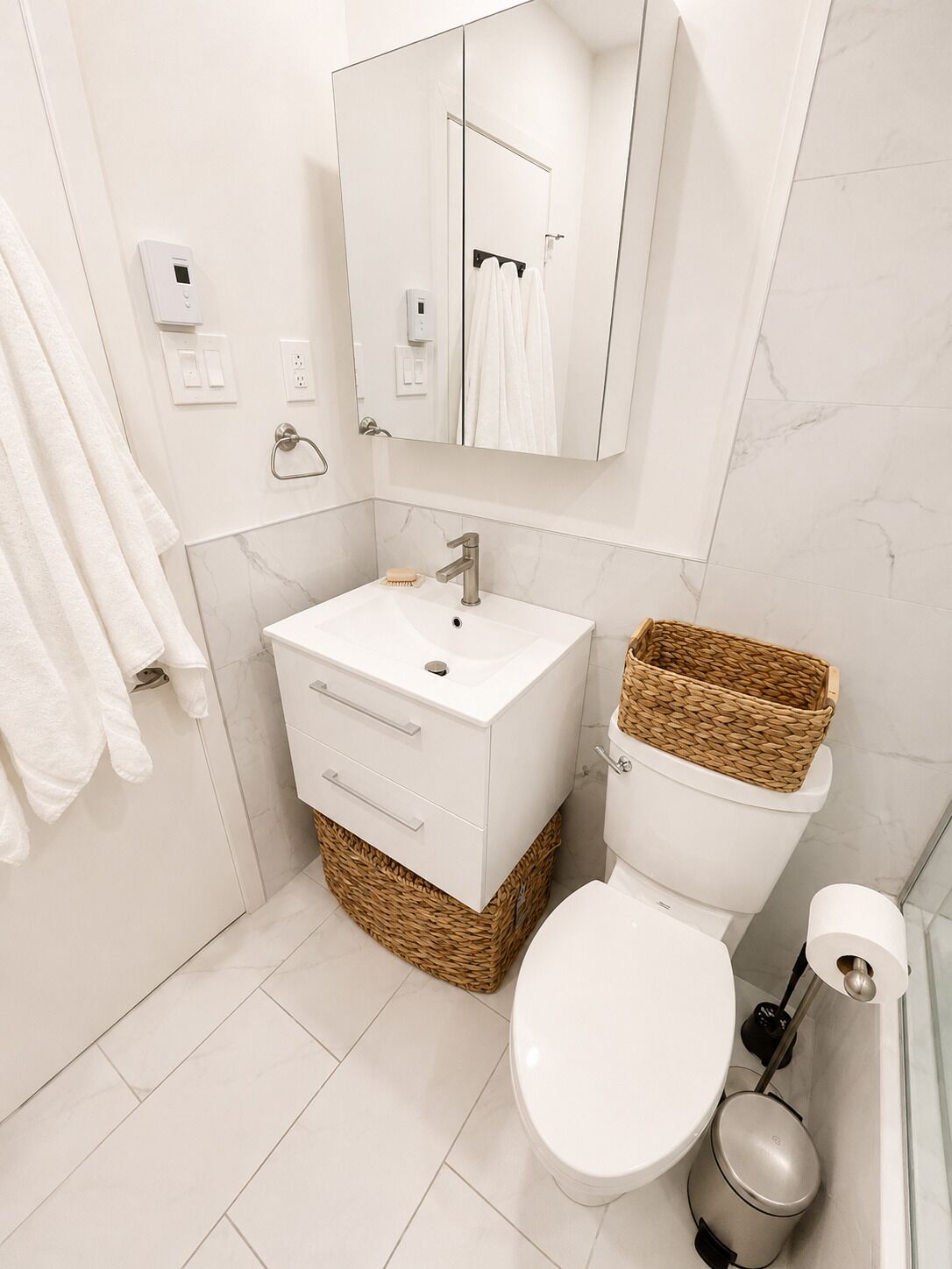 A modern bathroom with a white vanity, a toilet, a bidet, and a mirror.