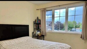 Ein Schlafzimmer mit einem Bett, einem Bücherregal und einem Fenster mit Blick.