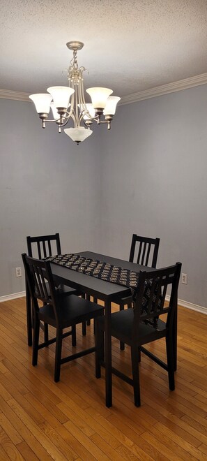 Une salle à manger avec un lustre, une table en bois et des chaises.