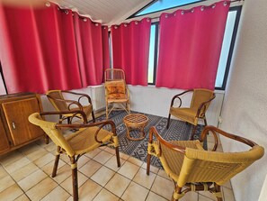 Une pièce comprenant quatre chaises en osier, une petite table ronde et un buffet.