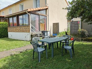 Une terrasse avec une table et des chaises, un espace extérieur couvert avec des fenêtres et un mur en briques.