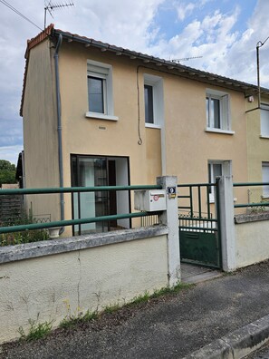 A two-story building with a beige facade, a green gate, and a number 9 sign. - House for 1–8 people, garden, 10 minutes from Futuroscope and downtown, French decor 1965-1970 (Poitiers)