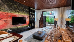 Een moderne woonkamer met een flatscreen televisie, een open haard, een eethoek en uitzicht op de omgeving.