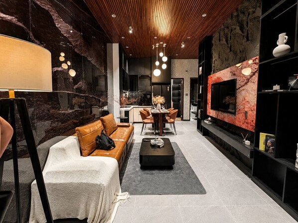 A modern living room with a leather sofa, a coffee table, and a TV on a red marble wall.